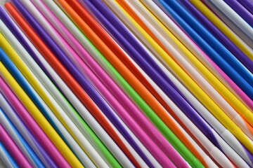 Multi-colored straws for drinks lie in a row parallel to each other.