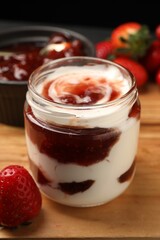 Tasty yoghurt with jam and strawberries on wooden board, closeup