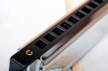 A metal harmonica with ten holes, a wind instrument, photographed on a wooden surface.