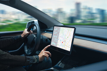 Person driving a car while interacting with a modern touchscreen navigation map in the dashboard..