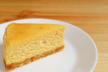 Slice of mouthwatering baked cheesecake on a white plate