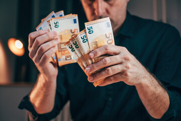Businessman counting fifty euro banknotes in office while working overtime