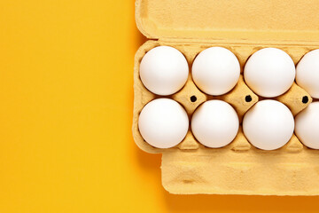 Eggs in a cardboard box, on a yellow background.