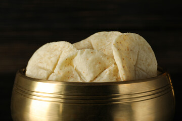 Bread in golden bowl on dark wooden background, close up