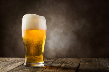 glass of blonde beer with foam on dark background.