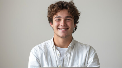A young man with curly hair smiling in front of a neutral background, wearing a white button-up shirt conveying a relaxed and friendly demeanor suitable for diverse commercial uses.