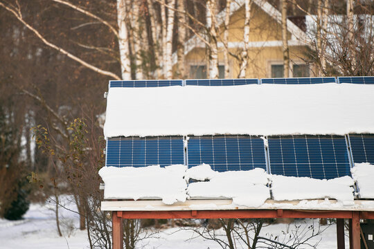 Solar panels are covered with snow in winter. Photovoltaic electricity installation during the winter season. Alternative energy home production in cold weather.