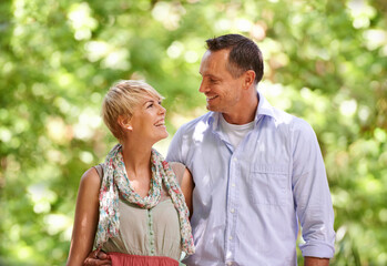 Obraz premium Hug, love and happy couple in a park for travel, adventure and bonding in nature together. Smile, romance and people embrace in a forest for summer date, reunion or weekend, holiday or fun vacation