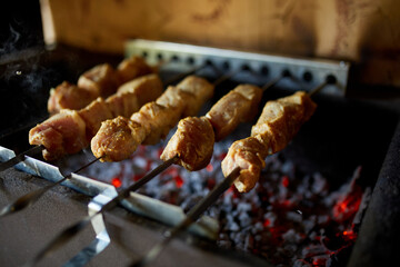 Skewers of kebabs cook over the hot coals of a barbecue grill in a home backyard setting, highlighting a summer culinary tradition.