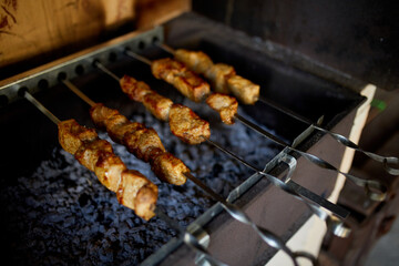 Skewers of kebabs cook over the hot coals of a barbecue grill in a home backyard setting, highlighting a summer culinary tradition.