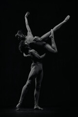 Fototapeta na wymiar Dynamic artistic pose. Young man and woman, ballet dancers making creative, passionate performance. Black and white. Concept of classic art, aesthetics, emotions, ballet dance, talent