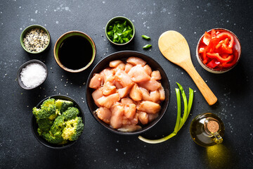 Chicken stir fry with soy sauce and vegetables at black background. Ingredients for cooking, recipe. Flat lay.