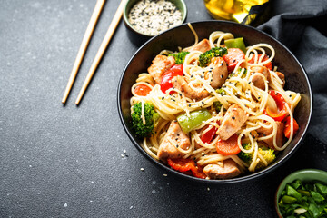 Stir fry chicken with vegetables and noodles at black background. Asian cuisine. Close up.