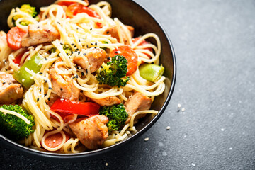 Stir fry chicken with vegetables and noodles at black background. Asian cuisine. Close up.