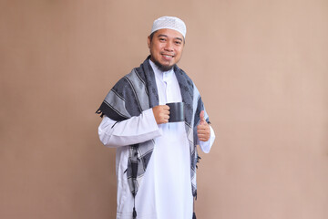 Asian Male Wearing Muslim Clothes Smiling While Holding Glass, Prepare for Breakfasting at Iftar...