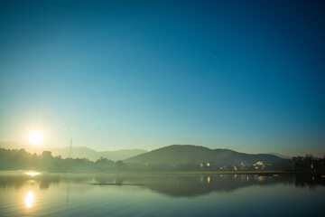 Fototapeta na wymiar Landscape of the sun slowly rising from the mountain. Morning sunrise at Vietnam's Lak Lake.