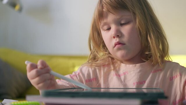 In a cozy living room, a delightful young girl happily sketches on her tablet with a stylus, reveling in the joy of creating art on the bright touch screen.