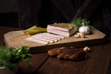 Homemade lard and deli meats sliced among vegetables and herbs