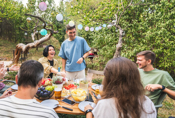 Group of happy young adults having fun at a barbecue party in the garden. Celebration, summer weekend and friendship concept