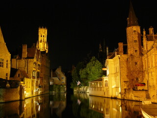canal at night, lined with old buildings of various heights and architectural styles. The water reflects the warm glow of the buildings’ windows and streetlights.
