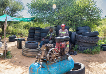 Fototapeta na wymiar millennial african american workers ,working on the side of the road changing and fixing tires, air compressor in the foreground