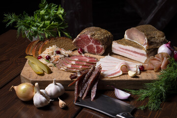 Homemade lard and deli meats sliced among vegetables and herbs
