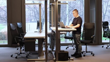 Businessman is working at ergonomic standing workstation in coworking office. Business concept. An IT specialist typing on laptop. SEO manager. A successfull result of online meeting. Overtime work