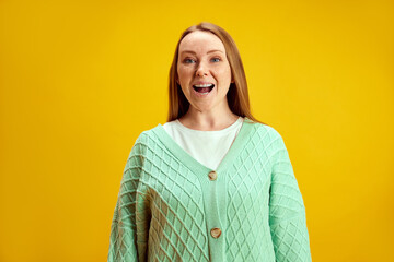 Shocked, surprised young ginger head woman looking at camera widely open mouth against yellow studio background. Model with freckles. Concept of beauty and fashion, self-expression, human emotions. Ad