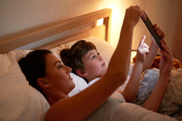 Mom, boy and tablet in bedroom at night for care, bonding and watch movies together in family...