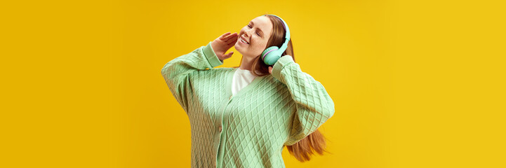 Banner. Young woman with ginger hair listening music with closed eyes and enjoy moment against...
