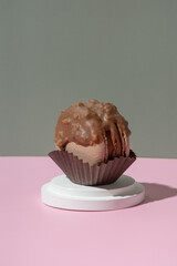 Chocolate macaroon on a podium on pastel pink-green background