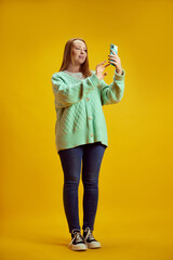 Full length portrait of young girl with red hair and freckles dressed smart casual outfit using...