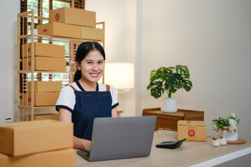 Startup small business entrepreneur or freelance Asian woman using a laptop with box, Young success Asian woman with her hand lift up, online marketing packaging box and delivery, SME concept.