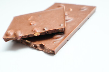 Milk Chocolate bar pieces with nuts on white background. Selective focus.