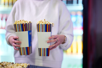 A vendor stands outside the cinema, holding freshly popped popcorn to sell to moviegoers before...
