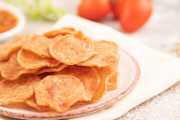 Slices of dehydrated salted meat chips on gray concrete, side view, selective focus