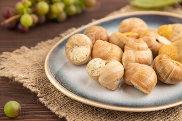 Grape (Burgundy) snails with butter and cheese on brown wooden, side view, selective focus