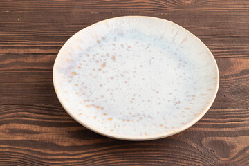 Empty blue and gold ceramic plate on brown wooden. Side view, copy space