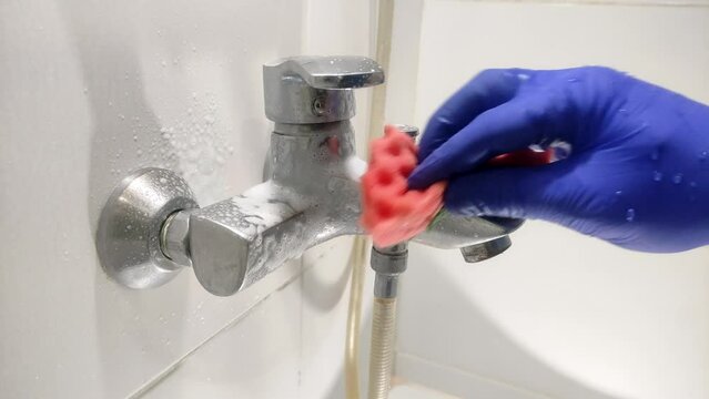 Housekeeper cleans bathroom fixtures with household chemicals