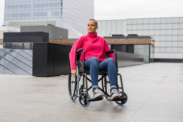 strong woman with shaved hair sitting in wheelchair