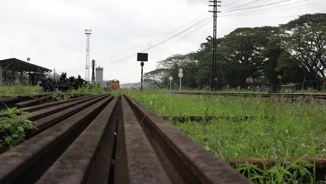 Low angle, front view of a locomotive of a local passenger train slowly running on train tracks after leaving a train station.