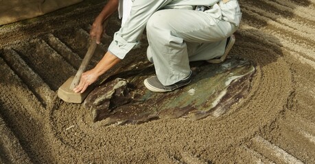 Close up of Gardener raking a Japanese Zen rock garden at Ginkakuji Temple or Silver Pavilion in...