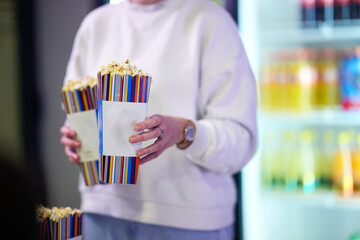 A vendor stands outside the cinema, holding freshly popped popcorn to sell to moviegoers before they enter the theater