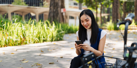 Obraz premium asian young businesswoman use smart phone while commuting in city. Eco friendly