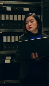 Vertical Video Private investigator organizes archived files for easy access, searching for old file cases to cross reference data. Law enforcement agent looking for classified folders in archive room
