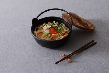 japanese udon noodles in a black bowl with chopsticks