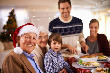 Family, portrait and grandparents at dinner on Christmas, together with food and celebration in home. Happy, event and kid smile with grandmother at lunch and relax at holiday, party or hosting meal