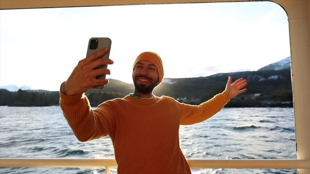 young man on ferry boat in Norway taking selfie photo with smart phone