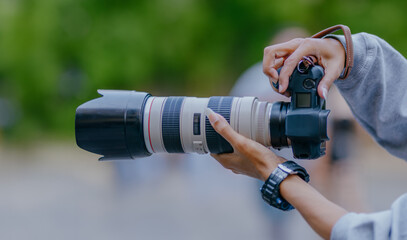 Man with camera and a big telephoto lens. Photographer outdoors with big zoom digital lens as...