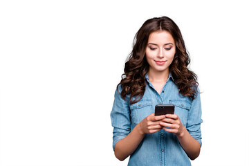Content calm trendy nice cute adorable lovely attractive brunette caucasian girl with wavy hair in casual denim shirt, playing game in phone, isolated over grey background
